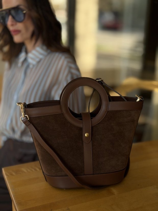 hnedá kožená crossbody kabelka s krátkymi ušami v ruke ženy