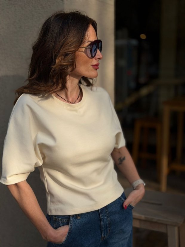 béžový vyúžený top s krátkym rukávom na žene v rifliach