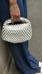 bielo šedá kožená kabelka s prepletanou štruktúrou kože v rukách modelky