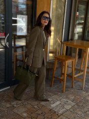 elegantný kostým v odtieni militare na žene sediacej pri stole