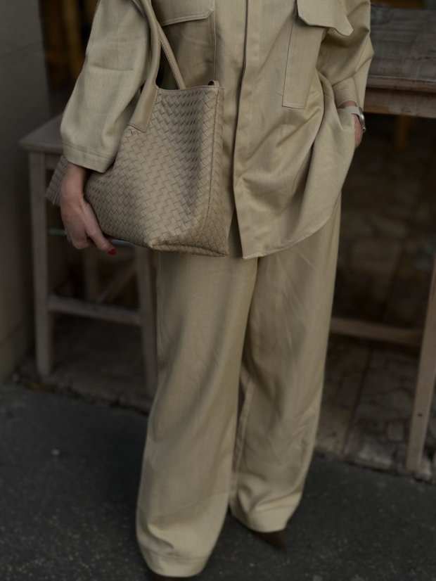 béžová shopper kabelka s prepletanou textúrou na ramene ženy