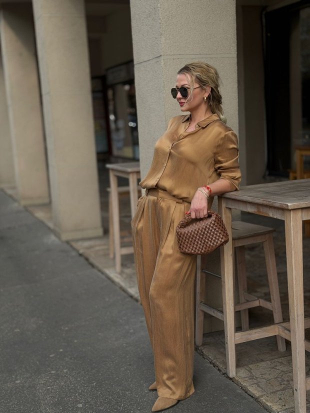 camel široké nohavice na žene s lesklou košeľou v elegantnom outfite