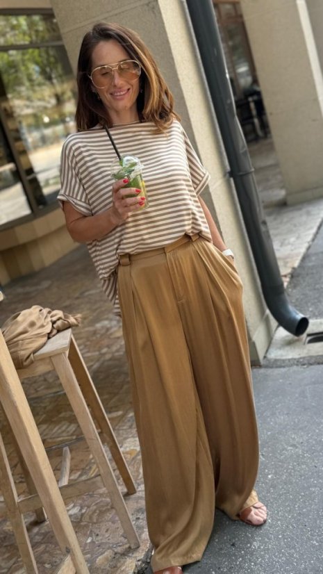 camel široké nohavice na žene s lesklou košeľou v elegantnom outfite