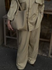 béžová shopper kabelka s prepletanou textúrou na ramene ženy