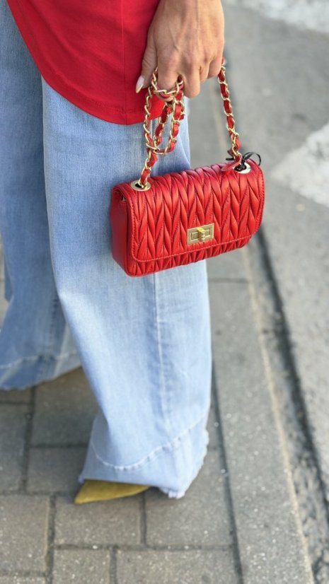 červená kožená mini kabelka so zlatou reťazou a prešívaným povrchom v rukách ženy