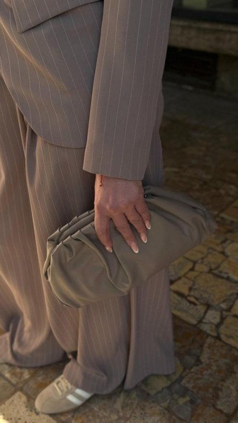 taupe kožená elegantná kabelka do ruky držiaca sa v ruke ženy