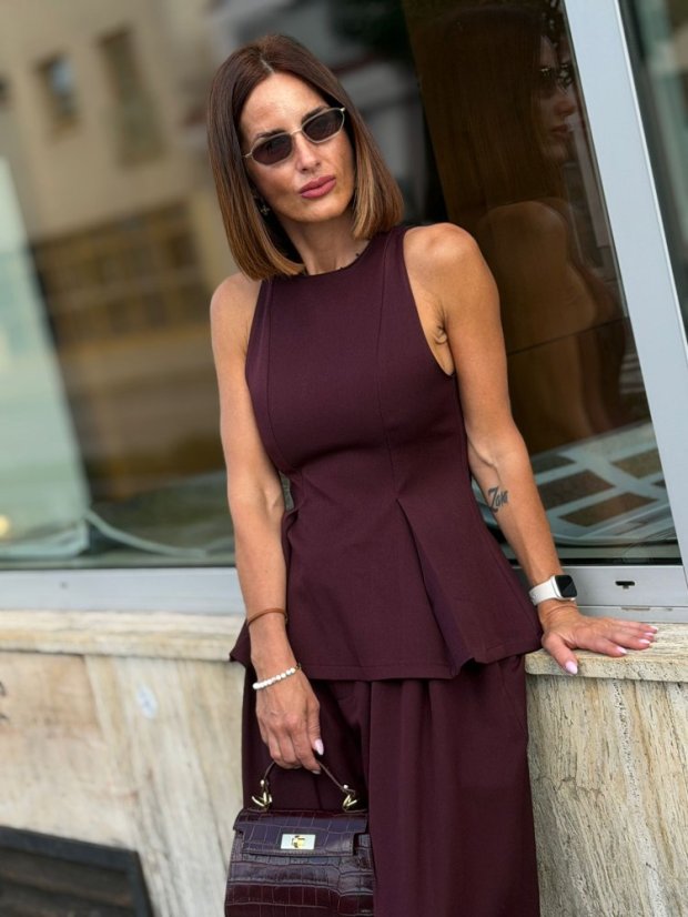 Dámska burgundy vesta Milano s tvarovaným strihom kombinovaná s nohavicami v rovnakom odtieni a mini kabelkou.
