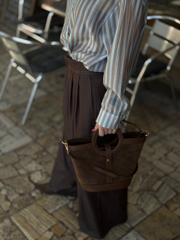 hnedá kožená crossbody kabelka s krátkymi ušami v ruke ženy