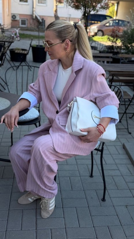 ružový elegantný kostým na žene so širokými nohavicami a bielou kabelkou