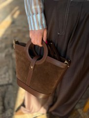 hnedá kožená crossbody kabelka s krátkymi ušami v ruke ženy