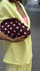 Bordová bodkovaná kabelka držaná v ruke v elegantnom mestskom štýle