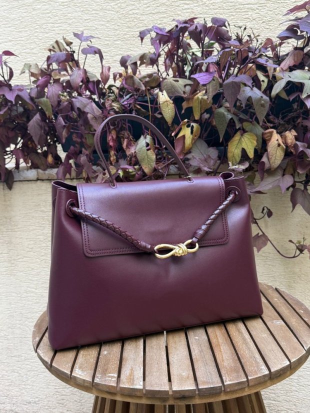 Burgundy kožená kabelka so zlatou sponou a prepletaným detailom, elegantný taliansky dizajn.