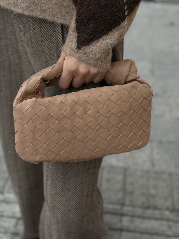 Béžová prepletaná kožená kabelka do ruky s elegantným tvarom.