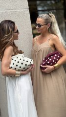 Bordová bodkovaná kabelka držaná v ruke v elegantnom mestskom štýle