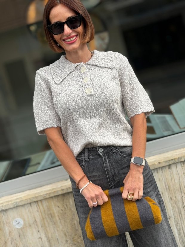 Sivý pletený sveter Giulia s krátkym rukávom, golierikom a gombíkmi na modelke.
