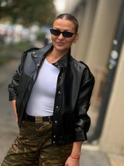Čierna bunda Mera v koženom vzhľade so zlatými patentmi a výrazným golierom na modelke.
