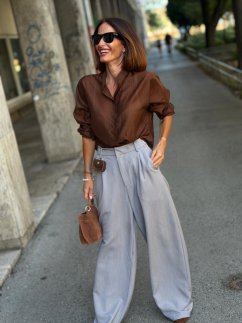 Hnedá blúzka Bellagio s košeľovým golierom a gombíkmi kombinovaná so svetlosivými elegantnými nohavicami. Hnedá blúzka Bellagio s košeľovým golierom a gombíkmi kombinovaná so svetlosivými elegantnými nohavicami.