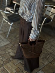 hnedá kožená crossbody kabelka s krátkymi ušami v ruke ženy