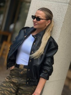 Čierna bunda Mera v koženom vzhľade so zlatými patentmi a výrazným golierom na modelke.
