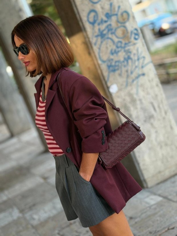 Prepletaná kožená kabelka Rena Burgundy v burgundy farbe na ramene modelky.
