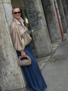 Mini prepletaná kabelka Lesi v taupe farbe z pravej kože s krátkym rúčkom na modelke.
