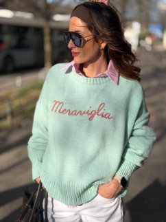 mentolový oversize sveter s nápisom na žene v mestskom outfite