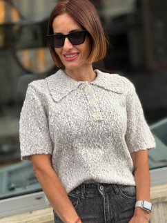Sivý pletený sveter Giulia s krátkym rukávom, golierikom a gombíkmi na modelke.