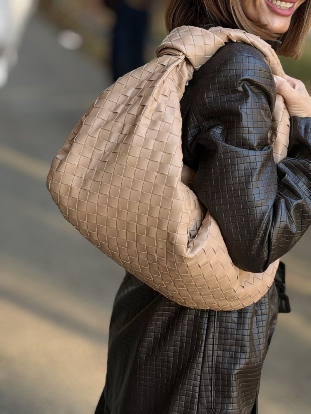 prepletaná kožená kabelka apricot držaná v ruke ženy pri elegantnom outfite